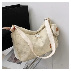 Detail of checkered canvas tote with round coin purse charm and wide shoulder strap