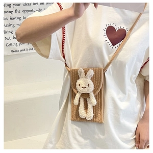 Détail d'un sac à bandoulière tissé marron avec un joli lapin en peluche blanc et une sangle
