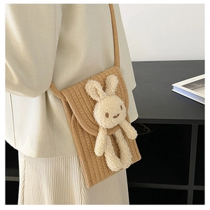 Détail d'un petit sac bandoulière tissé marron avec un lapin en peluche 3D mignon