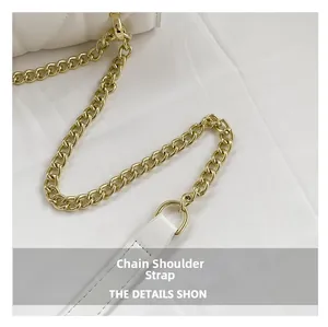 Macro view of gold chain strap and quilted white leather on a minimalist handbag