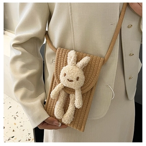 Détail d'un sac de téléphone en paille tressée avec décor de lapin en peluche sur mannequin