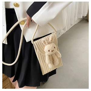 Détail du sac à bandoulière en coton beige tissé avec une poupée lapin en peluche