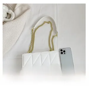 Quilted white crossbody bag with gold chain strap shown next to a smartphone for scale