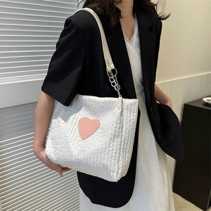 Borsa tote in tela bianca con cuore rosa e tracolla a catena indossata da modella