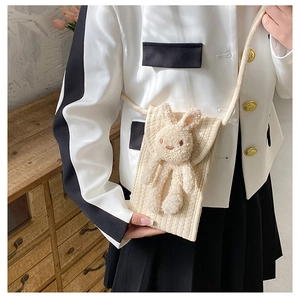 Détail d'un sac à téléphone beige au crochet fait main avec un adorable lapin en peluche