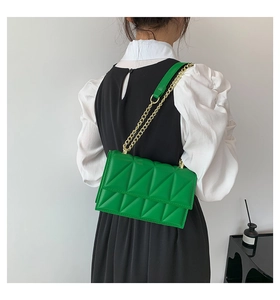 Fashionable bright green quilted crossbody bag with gold chain strap on a model