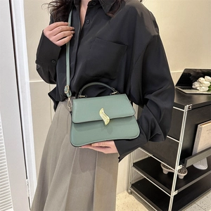 Elegant dark green trapezoidal handbag with gold buckle shown on a model