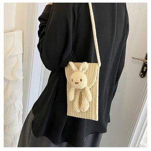 Détail d'un petit sac de téléphone tissé beige avec lapin en peluche et bandoulière
