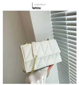 Close-up of white quilted chain bag with geometric triangular texture and gold strap