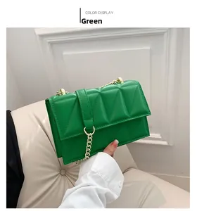 Detail of green quilted crossbody bag with gold chain and geometric triangle texture