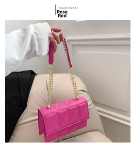 Detail of rose red crossbody bag with triangle quilted leather and gold chain strap