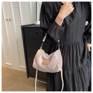 Détail d'un sac à bandoulière plissé avec poignée en perles et étiquette en cuir