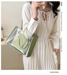 Detailed view of clear PVC tote bag with green synthetic leather trim and matching inner pouch