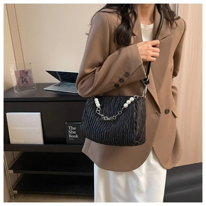 Détail du sac plissé noir avec grandes perles blanches et bandoulière en chaîne