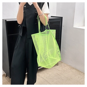 Grand sac fourre-tout en maille vert fluo porté avec une tenue d'été tendance et chic