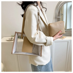 Detail shot of a clear PVC tote bag with khaki leather trim and matching inner pouch