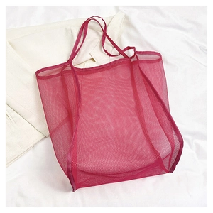 Detalle del bolso grande de malla magenta con asas reforzadas para playa y compras de verano