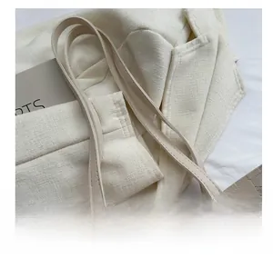 Close-up of beige quilted tote bag with thin handle and fashion label detail