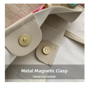 Detail of golden magnetic buckle on cream tote bag with contrast pink lining