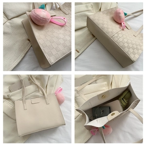 Detail view of large cream woven tote bag with magnetic closure and peach charm