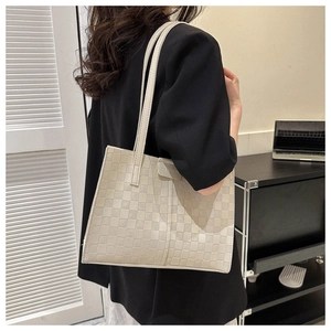 Detail of beige woven texture tote bag with Fashion label and long shoulder strap