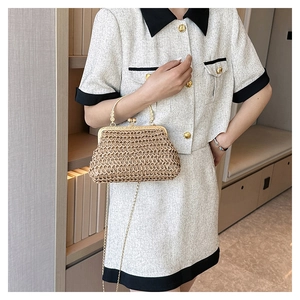 Detail einer handgewebten Strohtasche mit Metallrahmen und goldener Kette am Modell