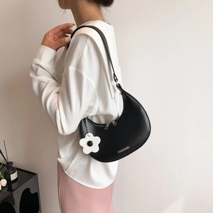 Fashionable black half-moon shoulder bag with white flower charm and textured finish