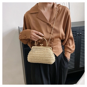 Dettaglio di una borsa in paglia intrecciata con chiusura vintage e catena dorata