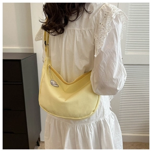 Detail of pale yellow nylon crescent bag with adjustable strap and cute puppy pendant