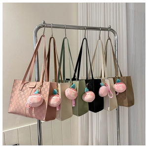 Row of colorful textured tote bags with checkered pattern and peach charms hanging on rack