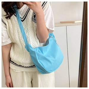 Close-up of a bright blue nylon crescent hobo bag with a matching wide fabric strap