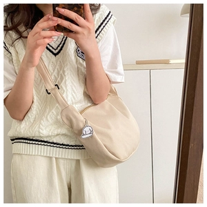Close-up of beige corduroy crescent crossbody bag with a cute white puppy pendant detail