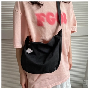 Detail of black nylon crescent crossbody bag with cute white cloud keychain accessory