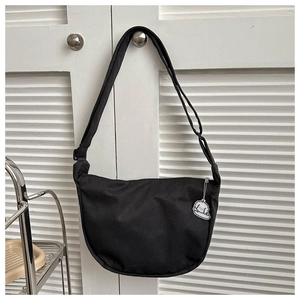 Detail of black crescent crossbody bag with adjustable strap and cute white dog charm