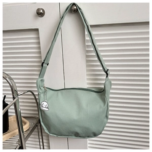 Detail of light green nylon crossbody bag with adjustable strap and cute animal pendant