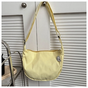 Detail of light yellow hobo canvas crossbody bag with adjustable strap and cute puppy pendant