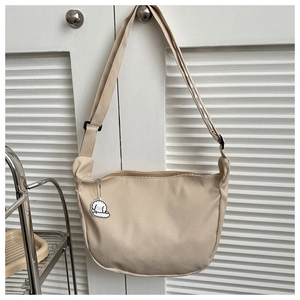 Detail of beige corduroy crescent bag featuring a soft texture and cute plush sheep charm