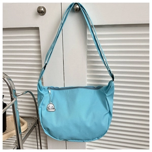 Detail of light blue nylon crescent bag showing grid texture and cute puppy charm