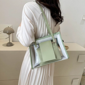 Green PVC transparent tote bag with leather inner pouch worn by a model in a minimal room