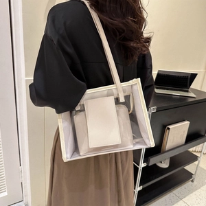 Transparent PVC tote bag with beige leather trim and inner pouch worn by a model