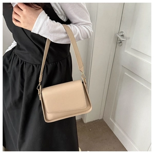 Detail of off-white minimalist crossbody bag with wide strap and gold metal hooks