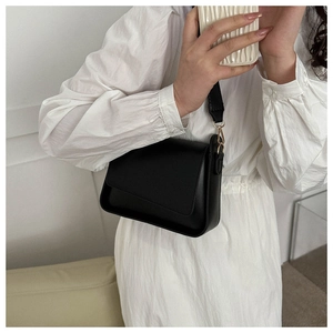 Detailed view of a black leather crossbody bag with elegant gold metal buckles