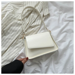 Close-up of minimalist cream white leather shoulder bag with gold metal hardware detailing