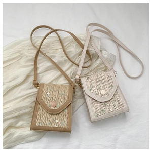 Detail of straw woven crossbody bags with floral embroidery on white fabric