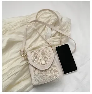 Close-up of small crossbody bag with floral embroidery and straw weave texture detail