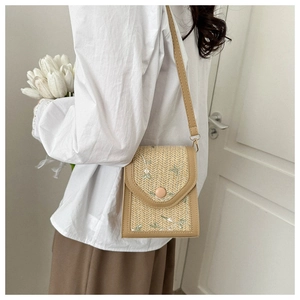 Detailed embroidery of light green flowers on a beige woven lace crossbody bag