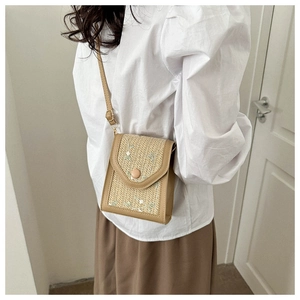 Detail of straw woven crossbody bag with green floral embroidery and adjustable strap