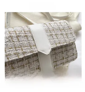 Detail shot of white tweed bag with gold metallic threads and elegant leather flap