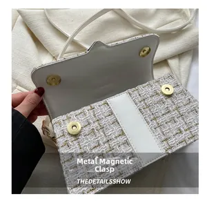 Detail view of the white tweed handbag showing the dual golden magnetic hardware buckles