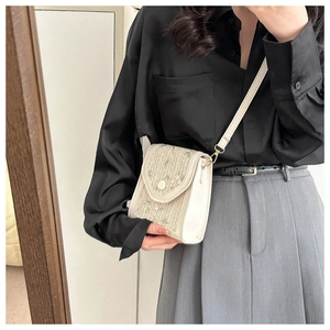 Close-up of beige woven crossbody bag with delicate green floral embroidery on model